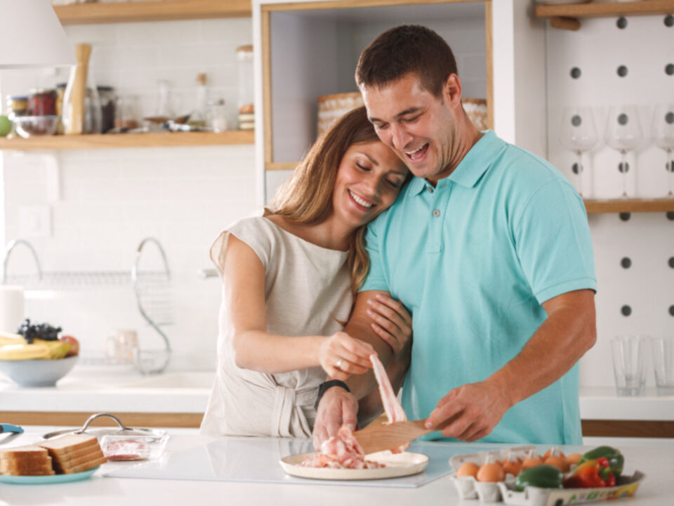 A couple cooking together in a bright kitchen