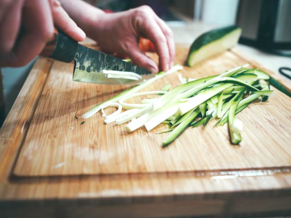 Hands slicing vegetables on a cutting board